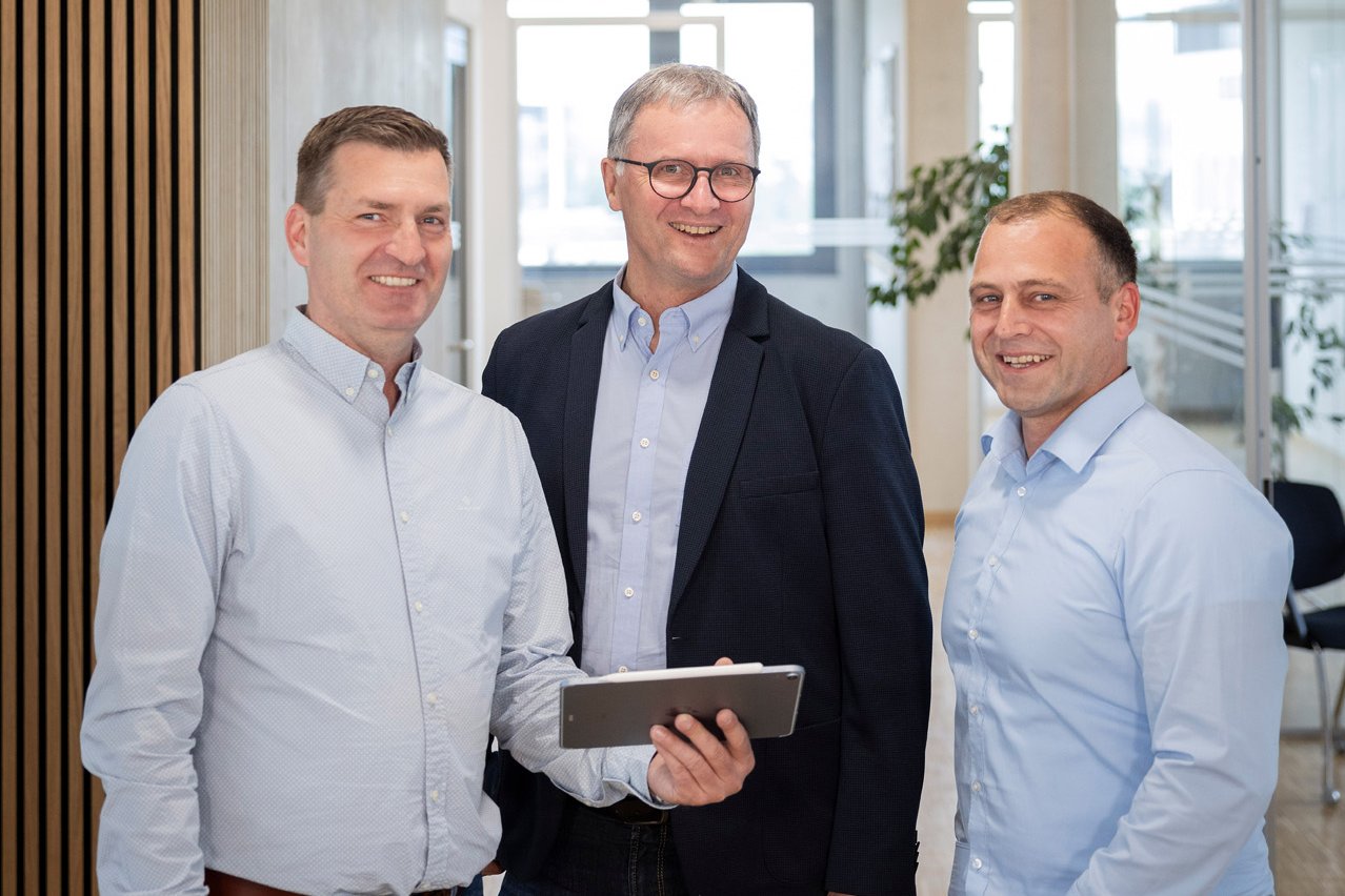 Drei Mitarbeiter der Wucher GmbH im Büroflur – professionelles Gruppenfoto.